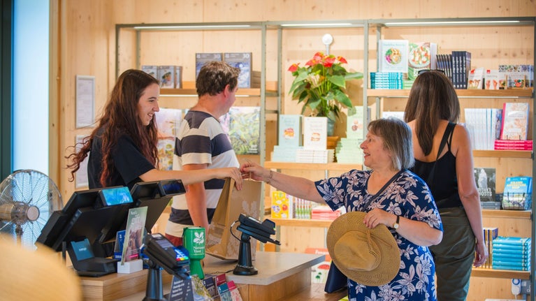 A visitor making a purchase at the shop counter at Winkworth Arboretum